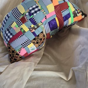 以下が含まれることがあります： ギンガムチェック、花柄、無地など、さまざまな色と柄のパッチワーク枕。 枕は丸みを帯びた形で、明るい緑色のストリップでアクセントがつけられています。 この装飾枕は、ユニークな家の装飾アイテムです。