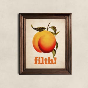 May include: A framed print featuring a peach illustration and the word "filth!" in orange text.