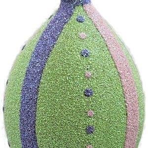 May include: Glittery Christmas ornament in a teardrop shape. The ornament features vertical stripes of green, purple, and pink glitter. Small dots of purple and pink glitter are also present, adding detail to the design. A silver metal cap tops the ornament.
