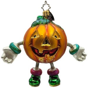 May include: A whimsical Halloween ornament shaped like a smiling pumpkin with arms and legs. The pumpkin is orange with a carved face, glittery accents, and green and red details. It has a star-shaped topper.