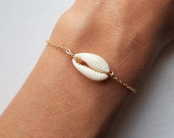 May include: A gold chain bracelet with a white seashell charm.