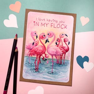 May include: A card with a watercolor illustration of pink flamingos in a pond. The card says "I love having you in my flock".