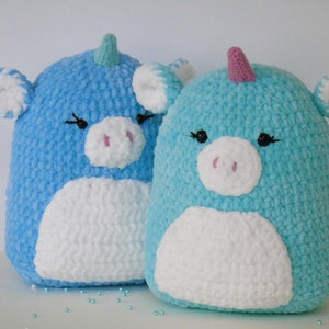 May include: Two crocheted unicorn plushies, one light blue and one turquoise, with white faces and pink noses.