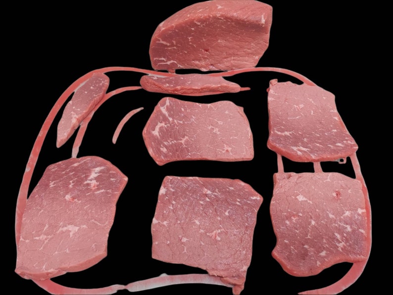 May include: Several raw beef slices, some thick and some thin, are arranged on a red surface. The beef is a light pink color and has a marbled appearance.