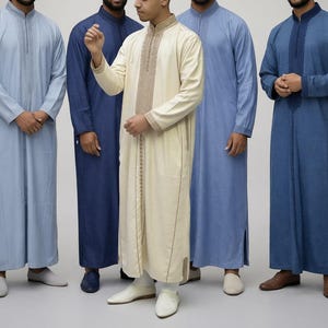 Puede incluir: Cinco hombres con túnicas largas de manga larga, en tonos azules y crema. Las túnicas tienen bordados decorativos alrededor del cuello y en la parte delantera. Las túnicas tienen aberturas laterales y se combinan con zapatos a juego.