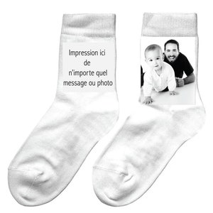 Op de afbeelding: Een paar witte sokken met een zwart-witfoto van een vader en kind op de ene sok en de tekst "Impression ici de n'importe quel message ou photo" op de andere sok.
