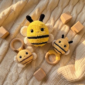 May include: A collection of handmade crochet bee toys and wooden blocks. The bees are yellow and black with white wings, and some have wooden ring attachments. The toys are arranged on a cream-colored knitted blanket.