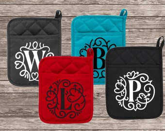 May include: Four quilted oven mitts with different colors and letters. The letters are W, B, L, and P. Each letter is surrounded by a decorative design.