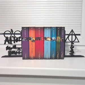 May include: A set of seven Harry Potter books with vibrant spines, arranged on a white windowsill. The books are supported by black metal bookends, one with the Deathly Hallows symbol and the other with the text "After all this time? Always".