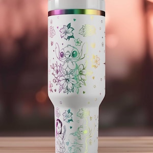 May include: White insulated tumbler with a lid and straw. The tumbler features a design of Stitch from Lilo & Stitch, surrounded by flowers and stars, with a rainbow iridescent finish. The design is in a line art style.