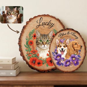 May include: Two wooden plaques with pet portraits. One features a cat with the word "Lucky" above it, surrounded by red poppies. The other has a Corgi and Cocker Spaniel with the text "Blue & Tracy" and purple flowers.