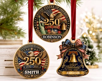 May include: Three circular and bell-shaped ornaments featuring United States 250th anniversary themes. Designs include the American flag, bald eagles, the Statue of Liberty, and the Liberty Bell with text reading 1776-2026, Robinson, Smith, and Anderson.