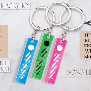 May include: Three acrylic keychains with a song code printed on them. The keychains are blue, green, and pink. Each keychain is 0.47 inches by 1.97 inches. The keychains are attached to silver keyrings.