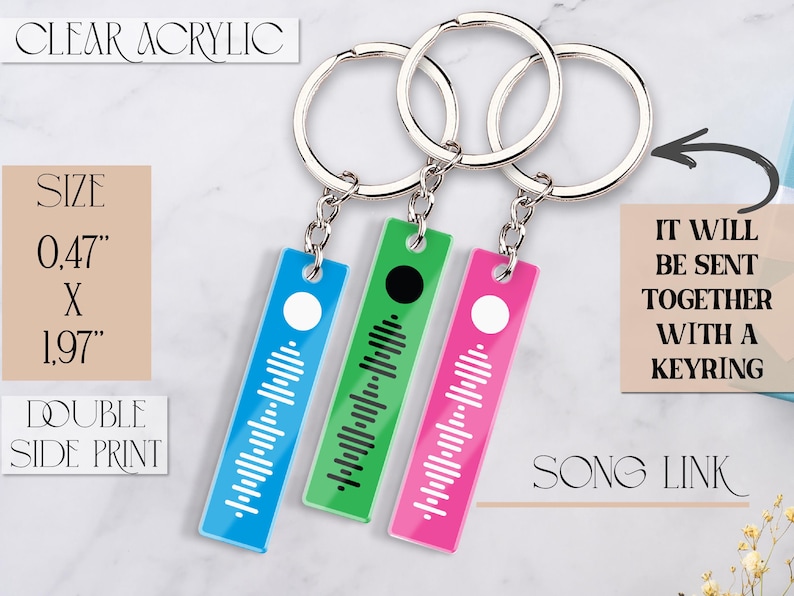 May include: Three acrylic keychains with a song code printed on them. The keychains are blue, green, and pink. Each keychain is 0.47 inches by 1.97 inches. The keychains are attached to silver keyrings.