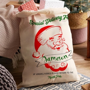 K&ouml;nnte beinhalten: Ein gro&szlig;er, cremefarbener Weihnachtsgeschenksack mit einer rot-gr&uuml;nen Weihnachtsmann-Grafik. Der Sack ist mit verpackten Geschenken gef&uuml;llt und tr&auml;gt den Text "Special Delivery For" und "Jameson". Auf der Unterseite des Sacks steht "If Undelivered Please Return to the North Pole."