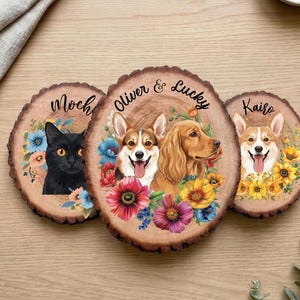 May include: Three wooden coasters with pet portraits. One features a black cat named Moch, surrounded by blue and pink flowers. Another has two dogs, Oliver and Lucky, with colorful flowers. The third coaster shows a dog named Kairo with yellow flowers.