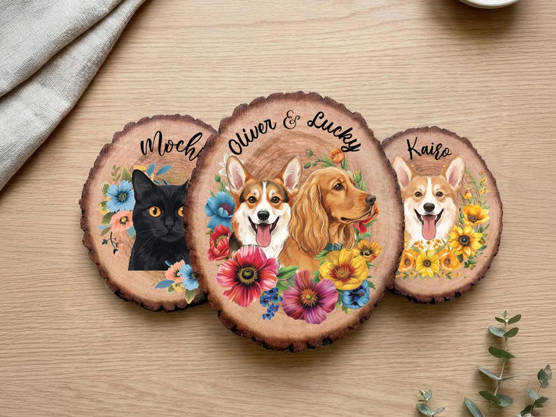 May include: Three wooden coasters with pet portraits. One features a black cat named Moch, surrounded by blue and pink flowers. Another has two dogs, Oliver and Lucky, with colorful flowers. The third coaster shows a dog named Kairo with yellow flowers.