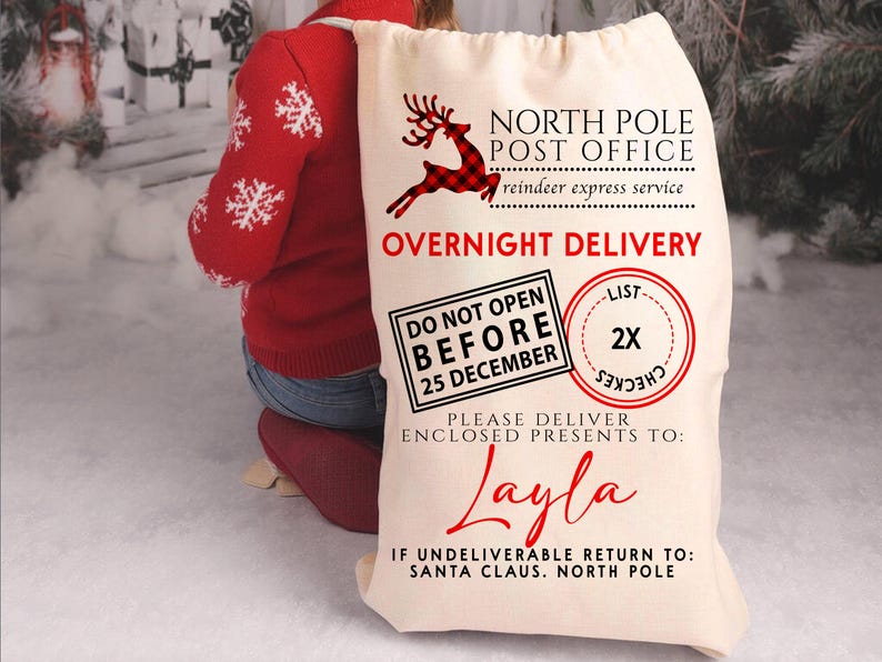 K&ouml;nnte beinhalten: Ein gro&szlig;er, cremefarbener Weihnachtsgeschenksack mit dem Text "North Pole Post Office" und "Overnight Delivery". Ein rotes Rentier-Motiv und der Name "Layla" sind ebenfalls sichtbar. Der Sack ist mit Geschenken gef&uuml;llt.