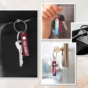 May include: A set of four keychains with colorful, abstract designs. Each keychain features a silver ring and a rectangular tag with a white circle and a black and white sound wave pattern. The keychains are shown on a black leather bag, a hand, a door, and a black wallet.