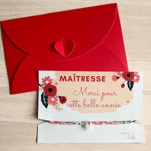 Peut inclure: Une enveloppe rouge avec un cœur décoratif et une carte avec l'inscription "MAÎTRESSE Merci pour cette belle année" ornée de motifs floraux. Un bracelet avec un charm en forme de cœur est également visible.
