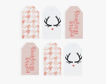 May include: Six pink and white gift tags with different designs. Two tags feature a pink and white houndstooth pattern. Two tags feature a reindeer head with black antlers and a red nose. Two tags feature the text "merry christmas" in pink.