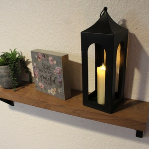 May include: A wooden shelf with a black metal lantern, a small potted succulent plant, and a gray wooden sign with the text "Start each day with a grateful heart".