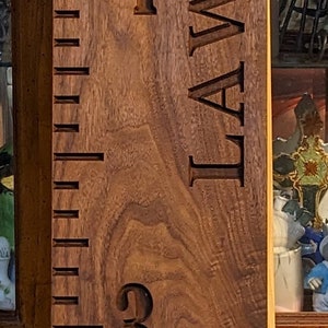 May include: A wooden growth chart with a ruler on the left side and the names "JAMISON & ELLIOT" engraved on the right side. The numbers 1 through 6 are engraved on the right side of the ruler.