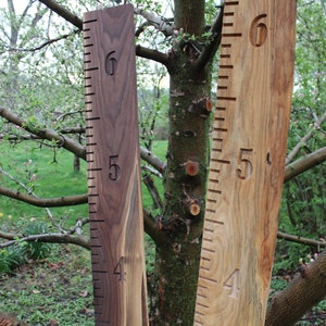 May include: Two wooden growth charts, one in a light brown wood and one in a dark brown wood, with numbers 3, 4, 5, and 6 carved into the wood.