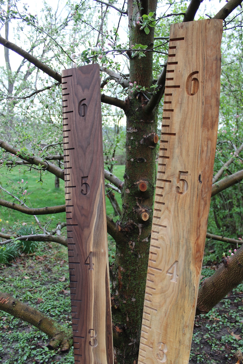 May include: Two wooden growth charts, one in a light brown wood and one in a dark brown wood, with numbers 3, 4, 5, and 6 carved into the wood.