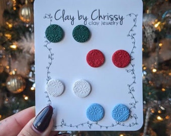 May include: A set of six Christmas-themed stud earrings. The earrings are made of polymer clay and feature a variety of snowflake designs in green, red, white, and blue.