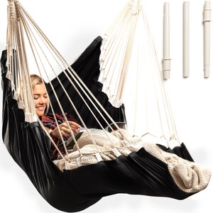 May include: A black and white hammock with a person sitting in it. The hammock is made of a soft, comfortable fabric and has a white rope.