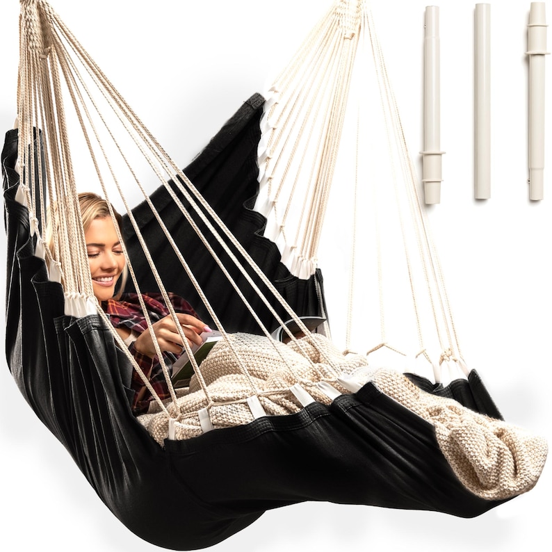 May include: A black and white hammock with a person sitting in it. The hammock is made of a soft, comfortable fabric and has a white rope.