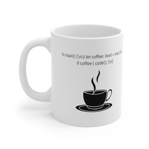 May include: White ceramic mug with a black coffee cup and steam design. The mug features the text "fn main() {
	 let coffee: bool = true;
if coffee { code(); }
}"