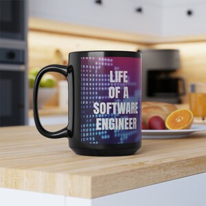 Peut inclure: Mug à café noir avec un motif blanc qui dit "Life of a Software Engineer". Le motif présente un fond bleu et violet avec un motif pixelisé.