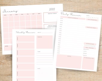 Può includere: Un set di pagine di pianificatore stampabili con uno schema di colori rosa e bianco. Le pagine includono un calendario mensile, un pianificatore settimanale e un pianificatore giornaliero. Il pianificatore giornaliero include sezioni per la pianificazione, il monitoraggio dell'assunzione di acqua e il monitoraggio dei pasti.