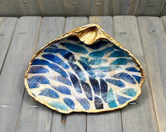 May include: A blue and white seashell dish with a gold rim. The dish is decorated with a pattern of blue and white leaves.
