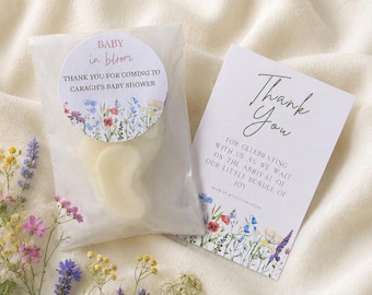 May include: A translucent favor bag containing a pale wax shape, sealed with a round sticker reading BABY in bloom THANK YOU FOR COMING TO CARAGH'S BABY SHOWER, alongside a rectangular card reading Thank You FOR CELEBRATING WITH US.