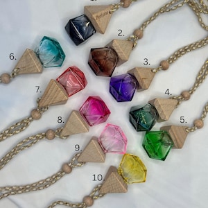May include: Ten different coloured glass perfume bottles with wooden triangle charms attached to a string. The bottles are shaped like diamonds and have a variety of colours, including blue, green, pink, purple, and yellow.
