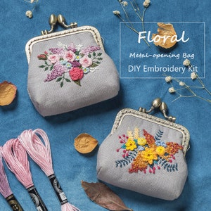 Puede incluir: Un kit de bordado DIY con dos monederos de tela gris con diseños de bordado floral. Un monedero tiene flores rosas y moradas, el otro tiene flores amarillas y naranjas. El kit incluye hilo de bordar en rosa y blanco.