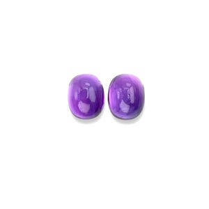 May include: Two oval-shaped amethyst cabochons, a purple gemstone, on a white background.