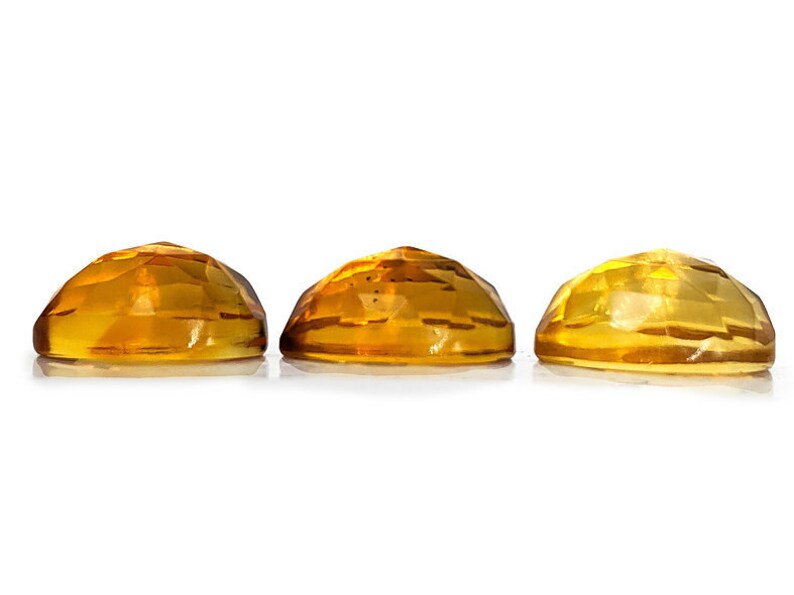 Yellow citrine gemstone cabochons.  Three rose cut cabochon stones seen from the side to demonstrate thick, high dome on stones.