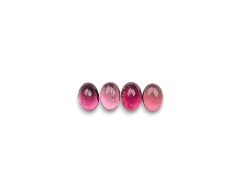 Pink tourmaline gemstone cabochons seen in light- to dark-pink.  Four smooth cut oval cabochon stones size 8 x 6 mm seen from the top.