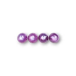 May include: Four faceted, round, purple gemstones are arranged horizontally against a white background. The gemstones have a polished, reflective surface, and are evenly spaced. The gems are a vibrant shade of purple, with a subtle play of light and shadow.