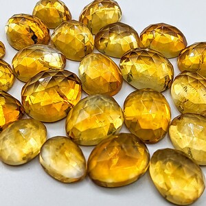 Multiple yellow citrine gemstone cabochons.  Rose cut cabochon stones in various sizes pictured to show variety of yellow shading.