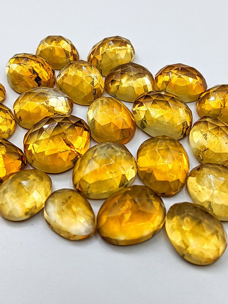 Multiple yellow citrine gemstone cabochons.  Rose cut cabochon stones in various sizes pictured to show variety of yellow shading.