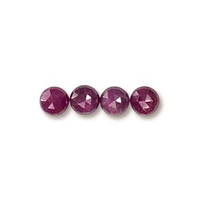 May include: Four round, faceted ruby beads in a deep red color.