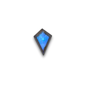 May include: A blue gemstone with a diamond shape, set in a silver-toned metal frame.