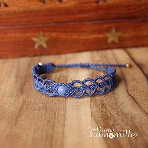 Könnte beinhalten: Ein blaues geflochtenes Armband mit einem hellblauen Edelsteinperle. Das Armband ist mit einer Knotentechnik hergestellt und hat ein schlichtes Design.