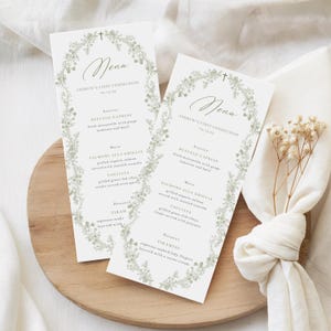 Può includere: Due menu di Prima Comunione con un design floreale. I menu sono bianchi con bordi floreali e testo verdi. Il testo include la parola "Menu" e il nome "Prima Comunione di Andrew". Gli elementi del menu sono elencati.