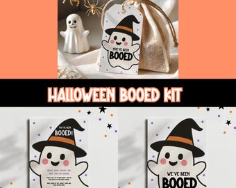 May include: A Halloween themed gift set featuring a small burlap bag with a tag that says "You've Been Booed" with a cartoon ghost wearing a witch hat. The image also includes a ceramic ghost figurine and decorative spiders.